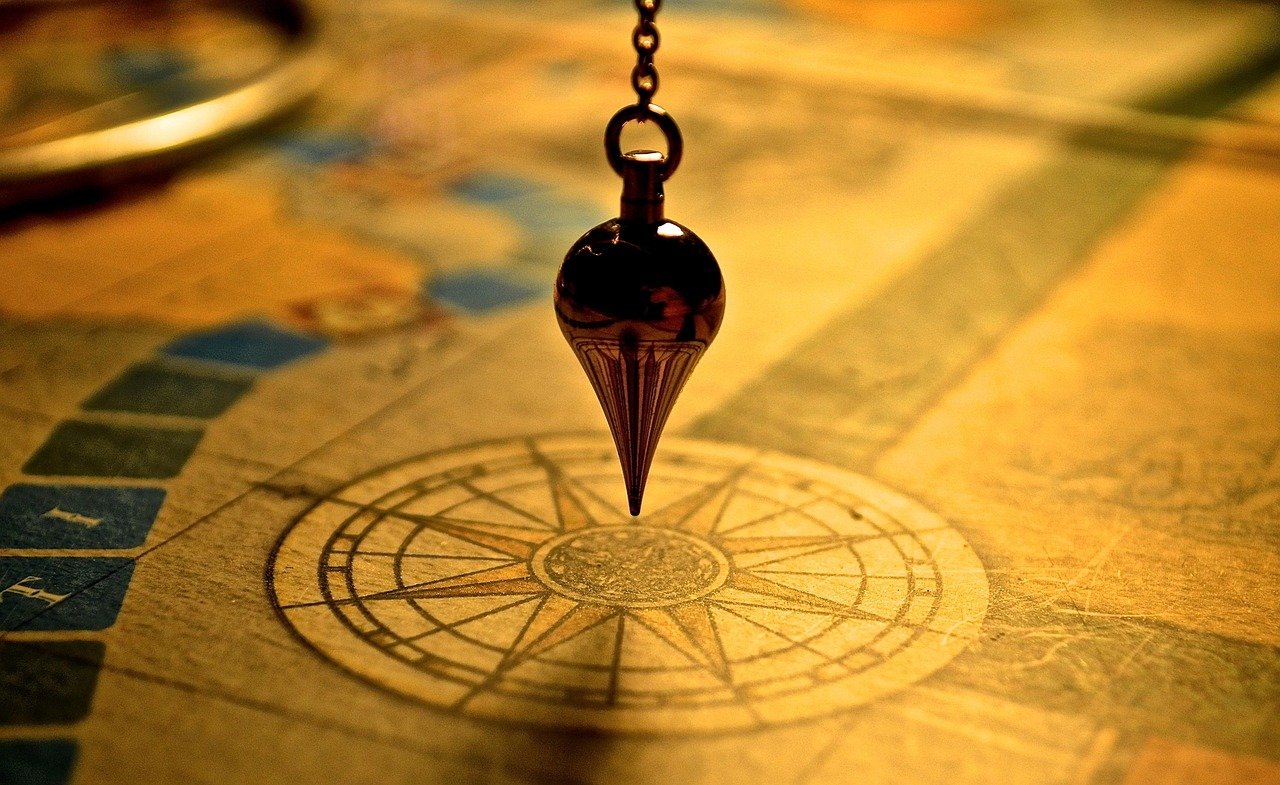 Pendule divinatoire au-dessus d'un cadran de radiesthésie